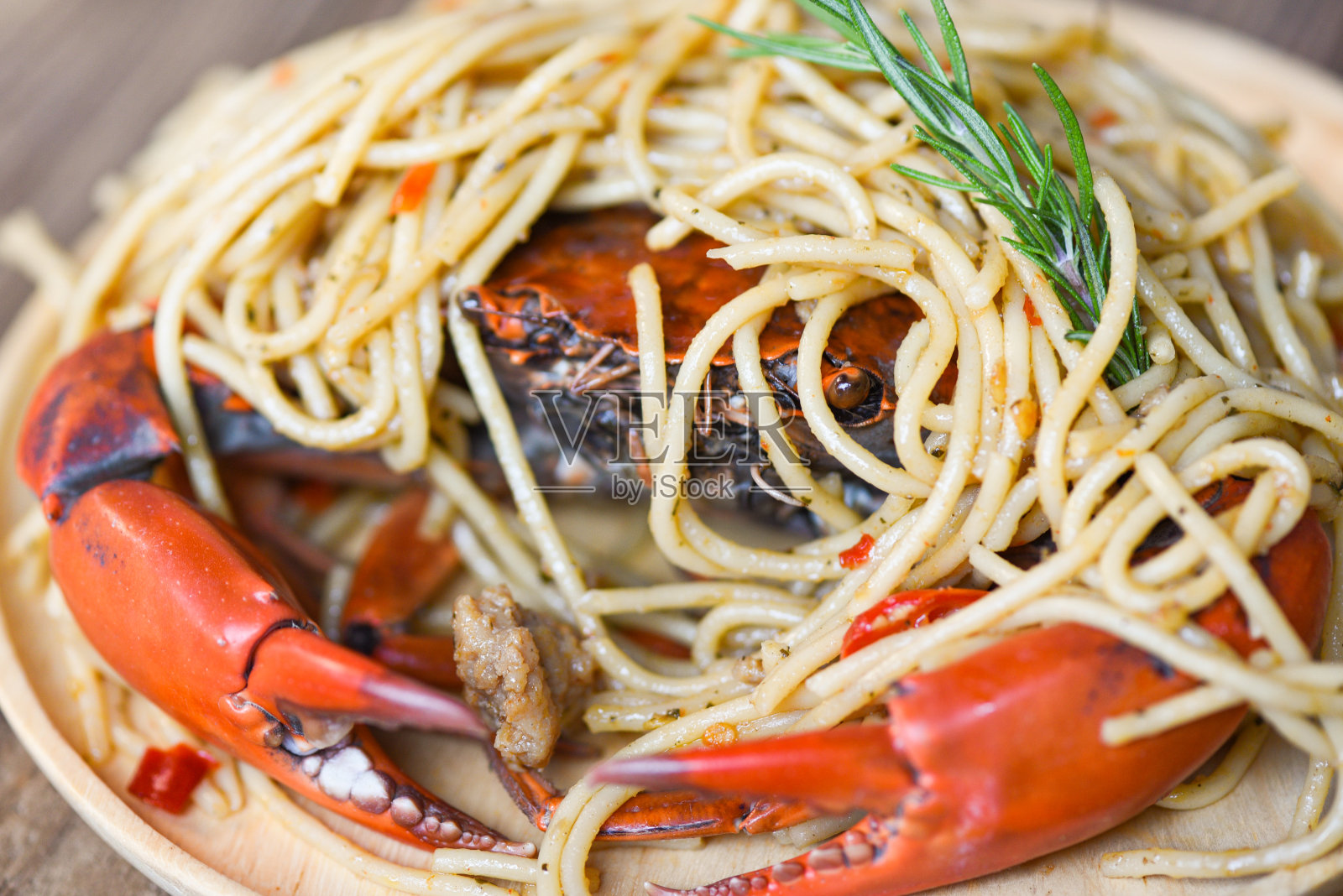 煮熟的螃蟹上碟，配上香料和意大利面海鲜，餐桌上的食物背景是煮熟的螃蟹。照片摄影图片