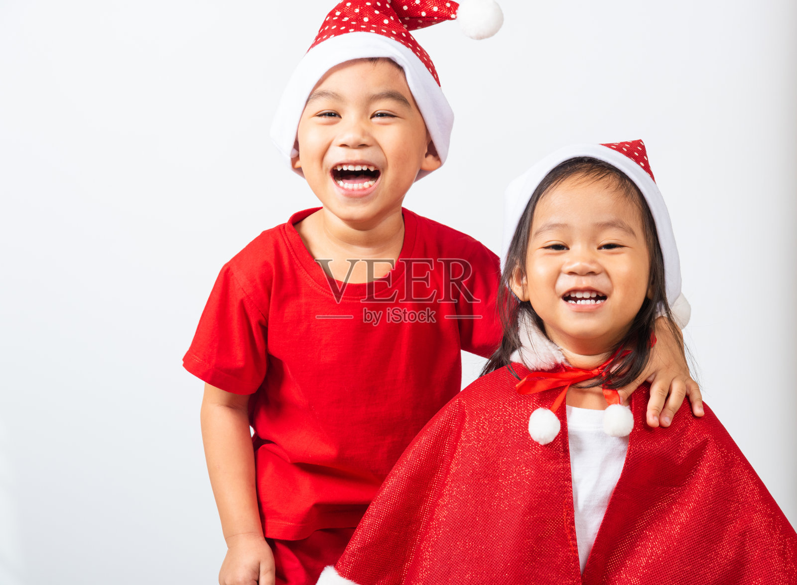 孩子们穿着红色的圣诞老人帽拥抱在一起照片摄影图片
