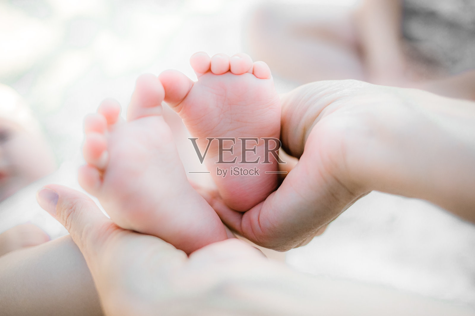 母亲轻轻地把婴儿的小脚放在她的手中。父母对新生孩子的爱和感情。照片摄影图片