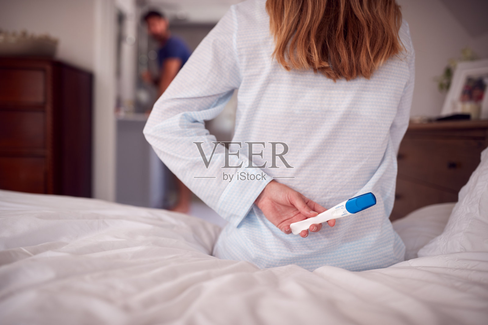 近距离观察穿着睡衣的女人在卧室里抱着阳性怀孕测试照片摄影图片