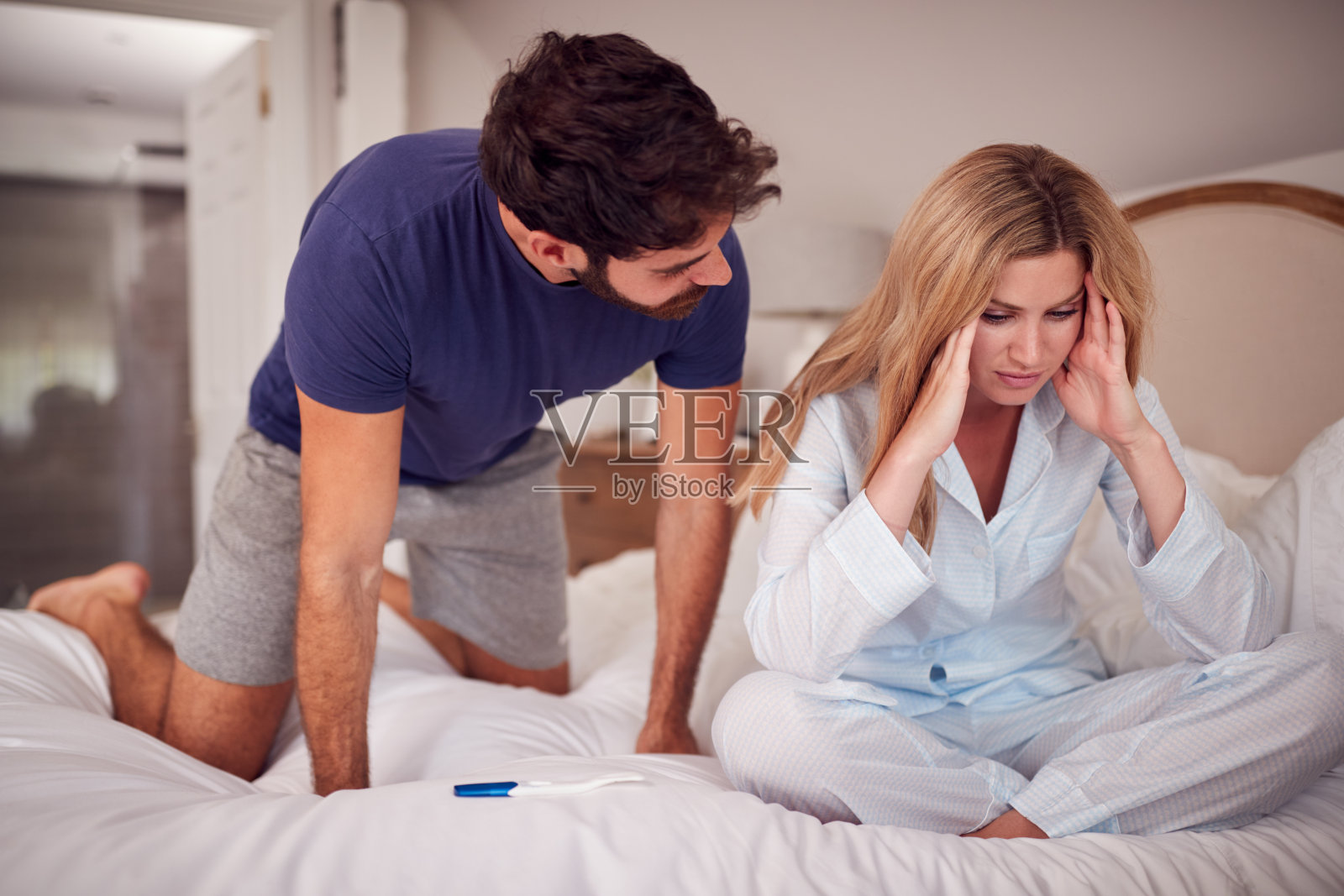 失望的夫妇穿着睡衣在卧室里拿着验孕棒照片摄影图片