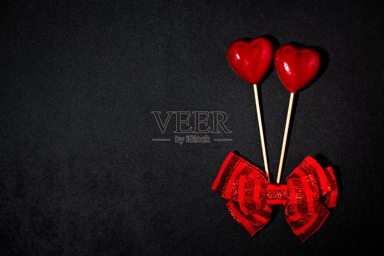 两颗带蝴蝶结的心在情人节的黑色背景上，俯视图照片摄影图片