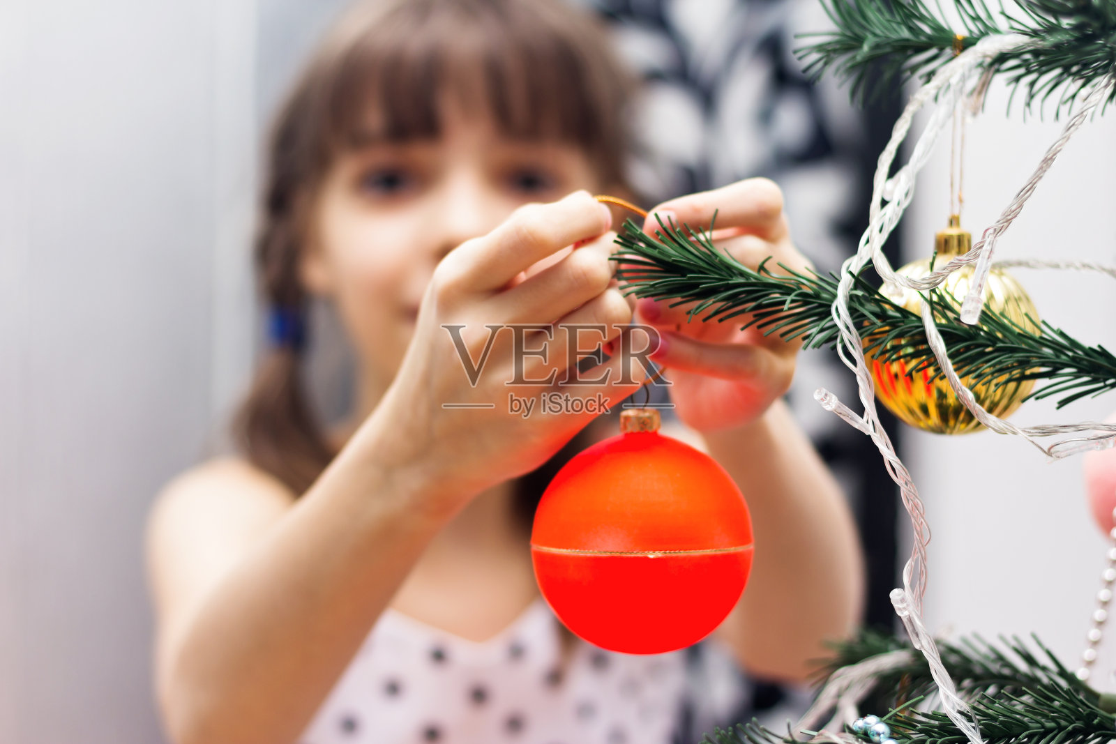 女孩正在装饰圣诞树。照片摄影图片