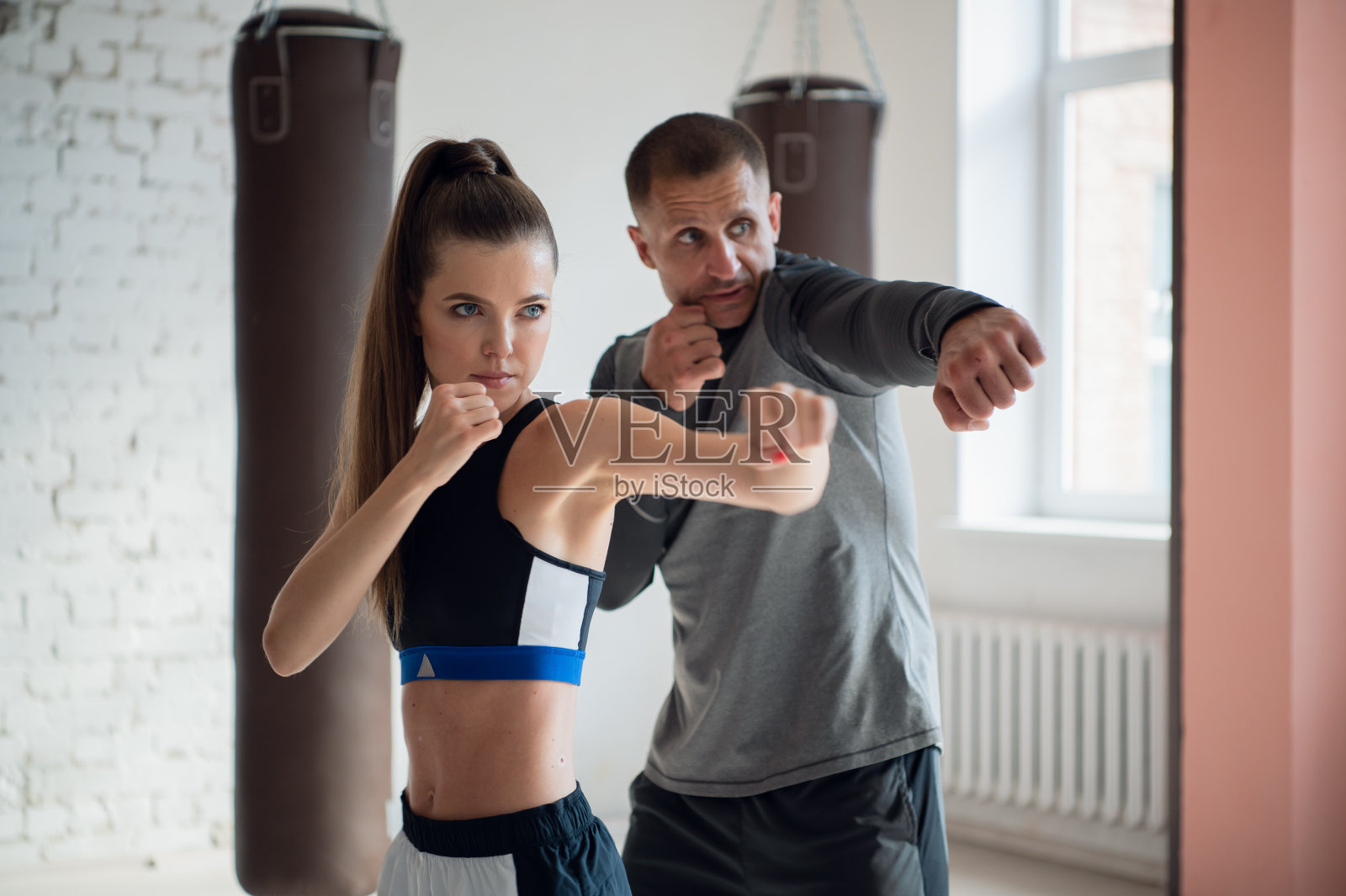在一间宽敞的阁楼里，一位男教练和他的女学员正在进行拳击训练照片摄影图片