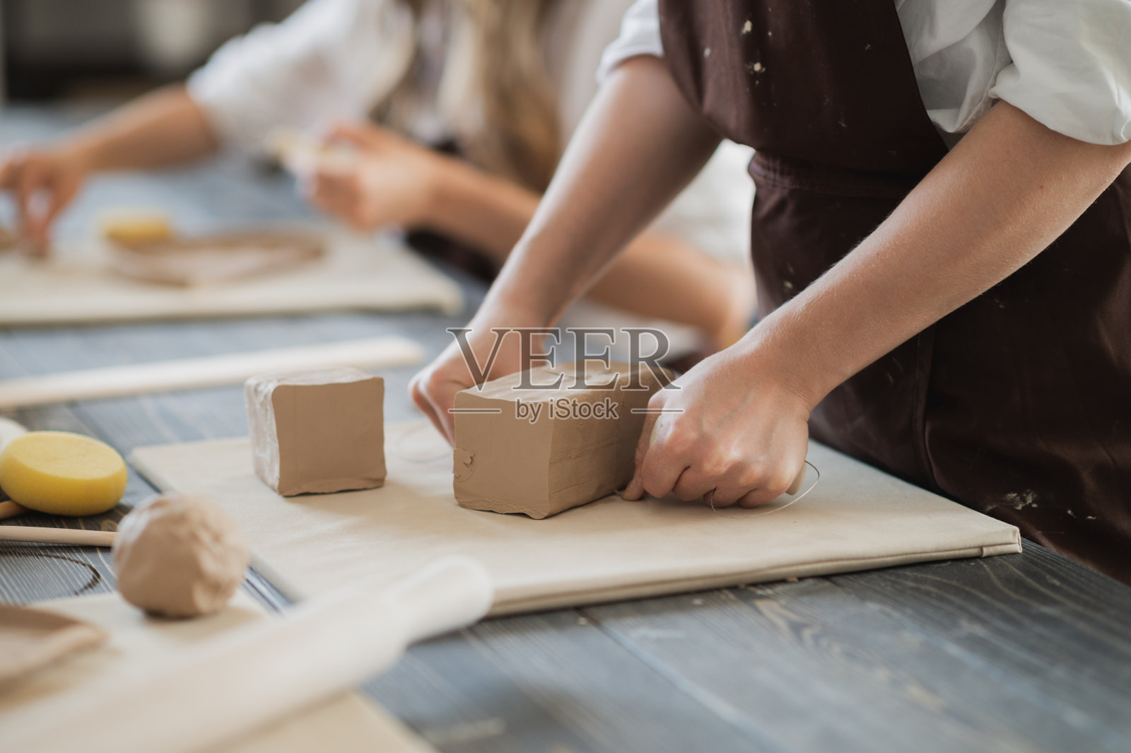 白粘土准备工作。在一个陶工车间里为雕刻切割粘土块层特写。陶制的旧木桌上有一排未加工的粘土照片摄影图片