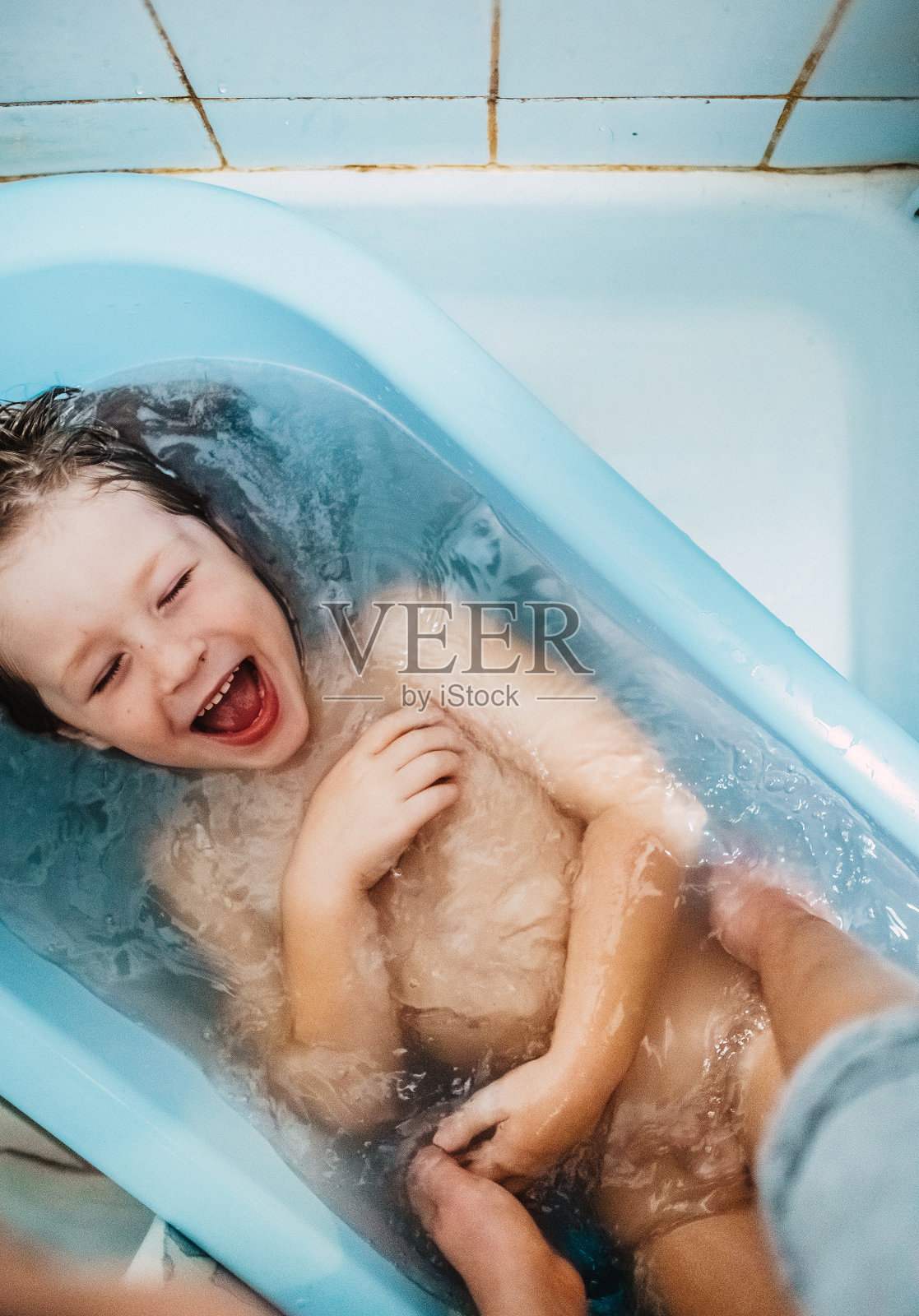 小孩子在淋浴下玩得很开心照片摄影图片