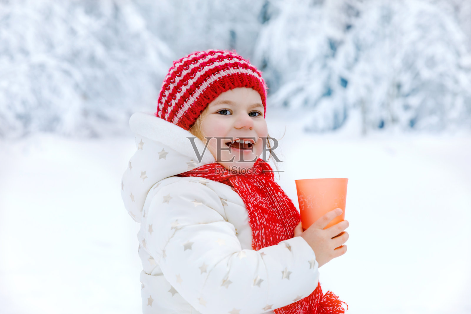 可爱的蹒跚学步的女孩喝热巧克力在冬天的森林。快乐健康的孩子与一杯热气腾腾的可可或茶，户外。33、活跃家庭休闲，漫步雪景。照片摄影图片