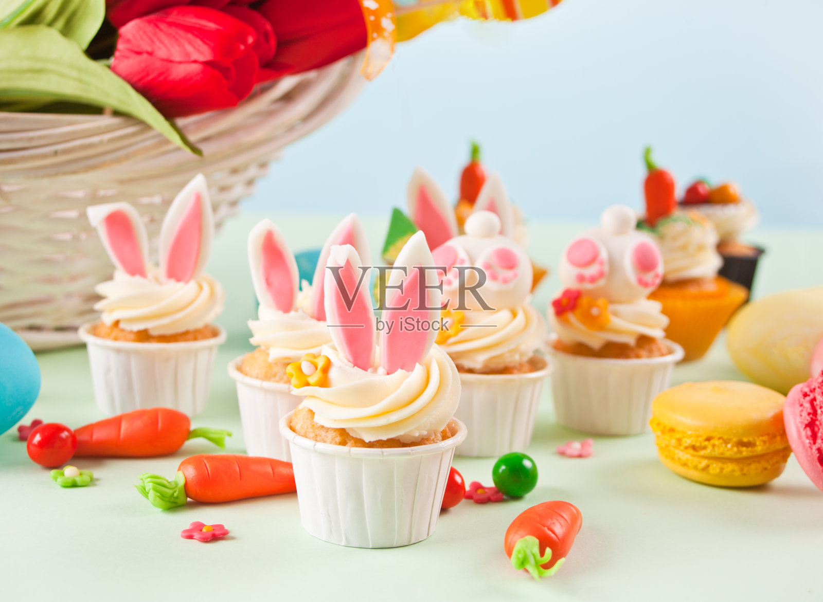 复活节搞笑兔子纸杯蛋糕。复活节庆祝节日餐桌。一篮花，背景是郁金香。照片摄影图片