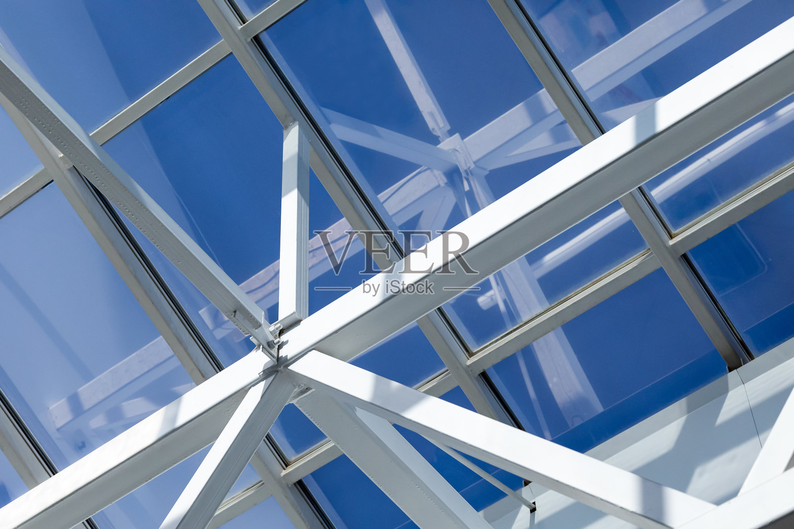 仓库、商场或办公中心的玻璃屋顶的钢框架。天花板由金属梁组成，通过螺栓和焊接连接，以保持流动性和刚性。照片摄影图片