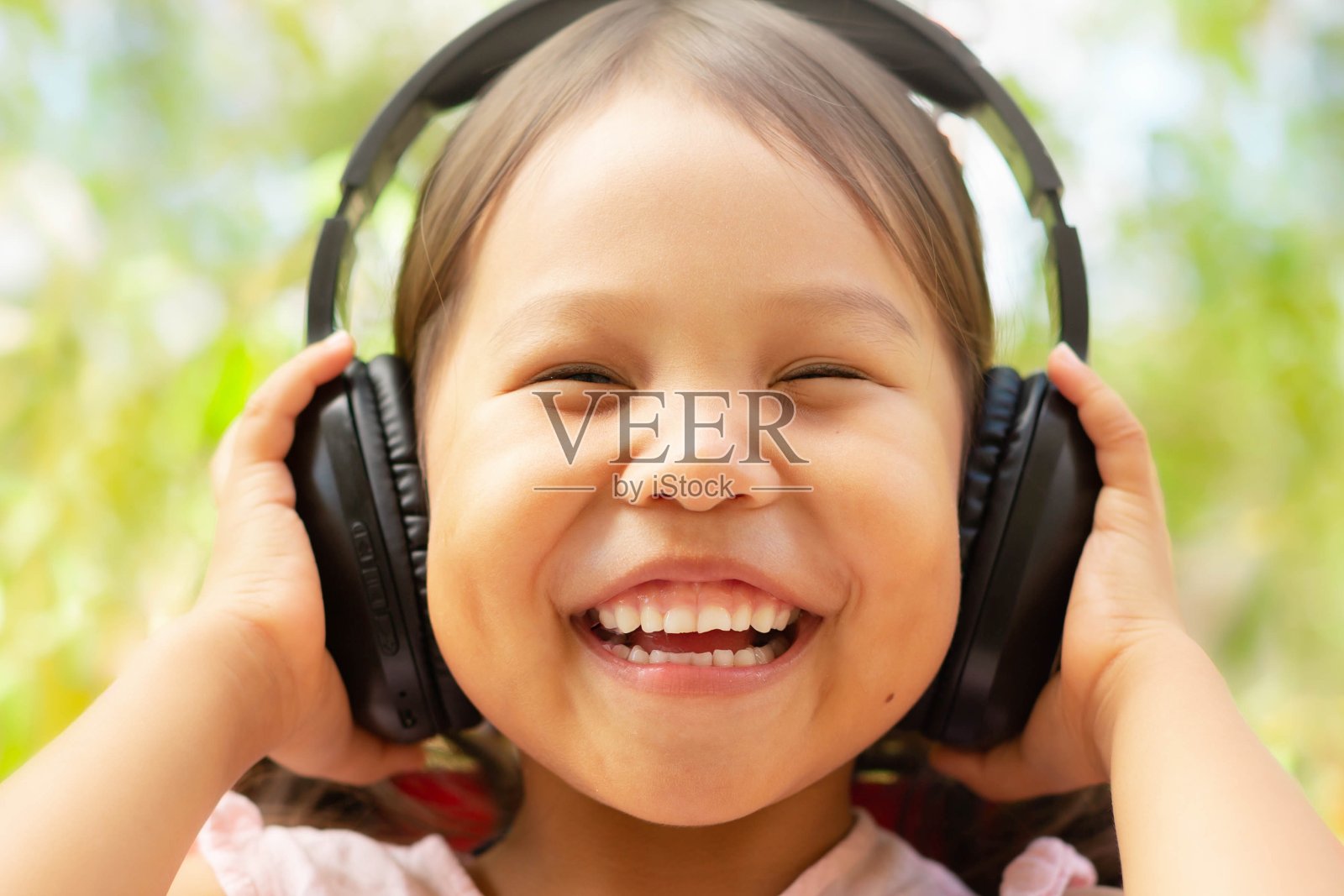 一个快乐的孩子戴着耳机听音乐。照片摄影图片