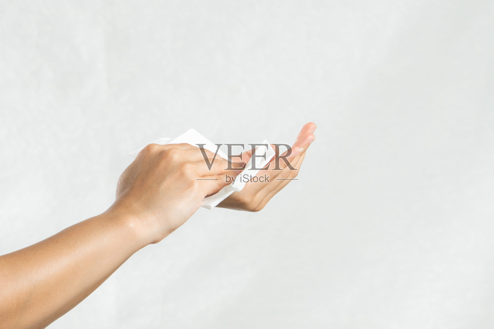 一个女人正在用白色的软纸巾擦手。孤立在白色背景上照片摄影图片