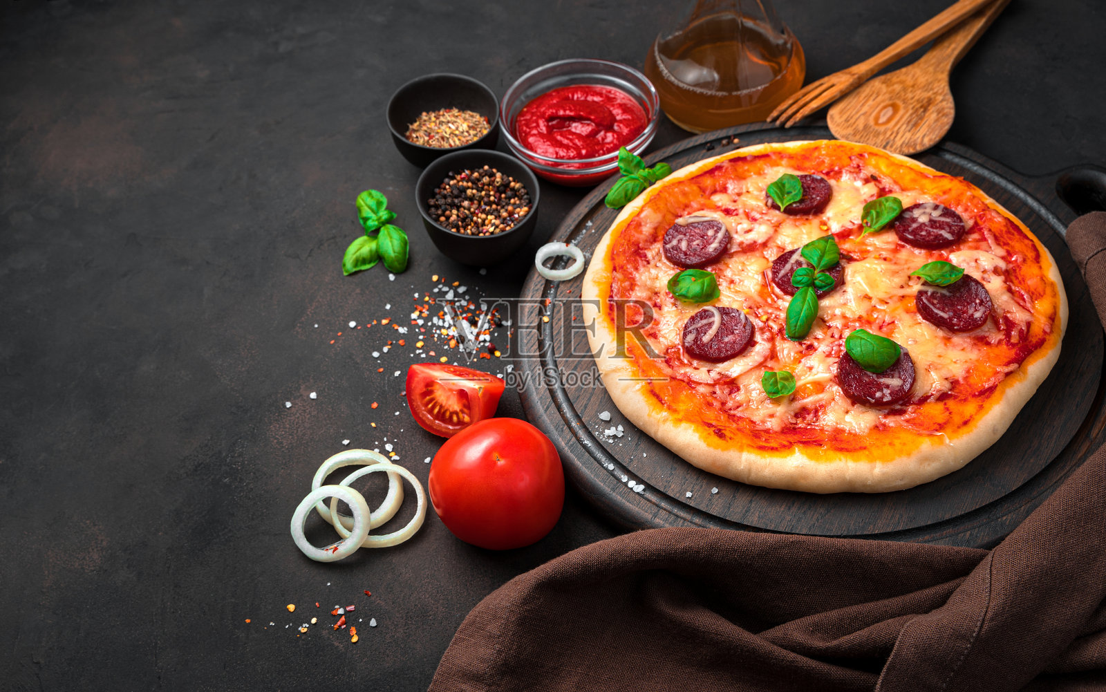 棕色混凝土背景下的意大利腊肠、奶酪和番茄披萨照片摄影图片