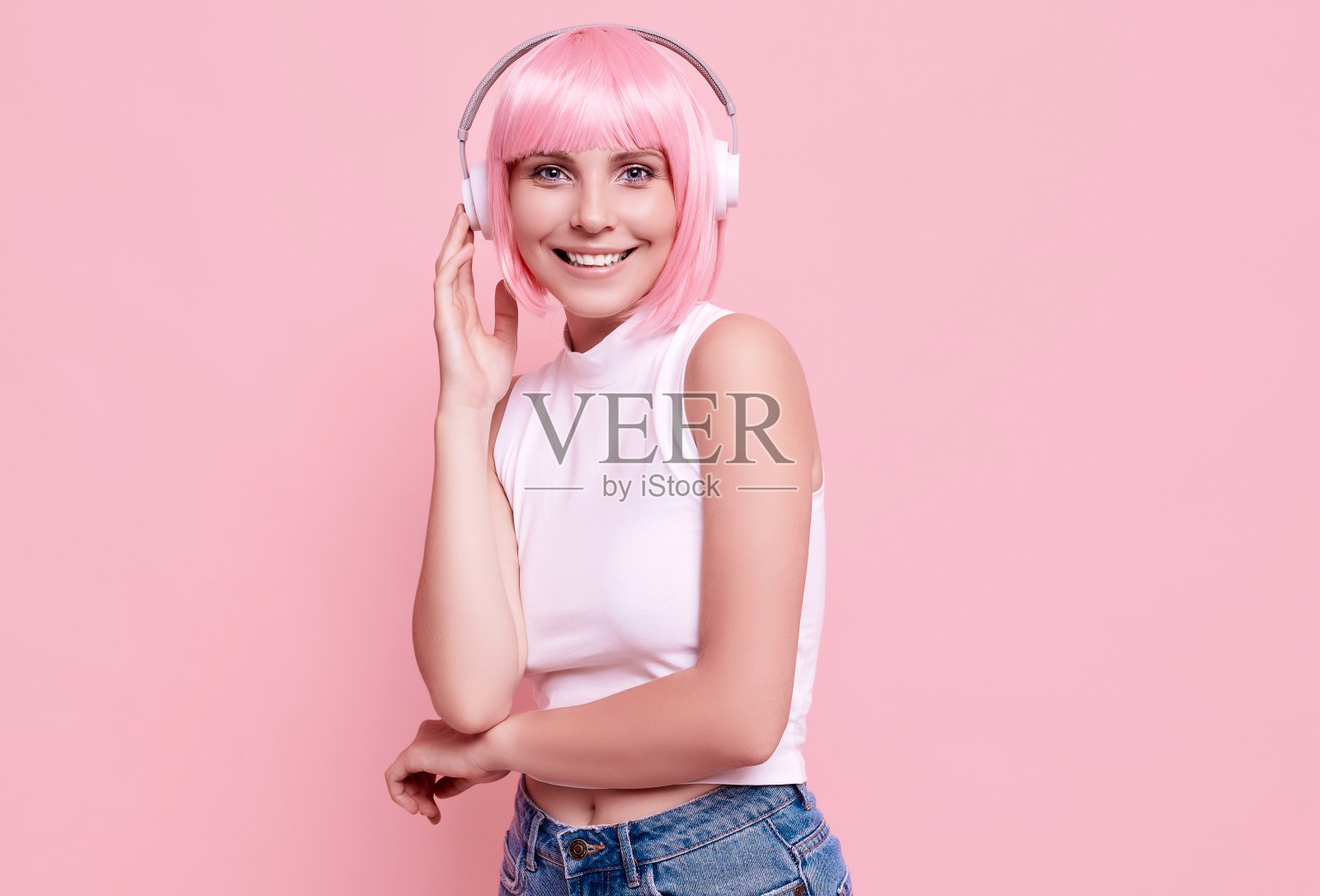 亮粉色头发的时髦女孩戴着耳机听音乐照片摄影图片