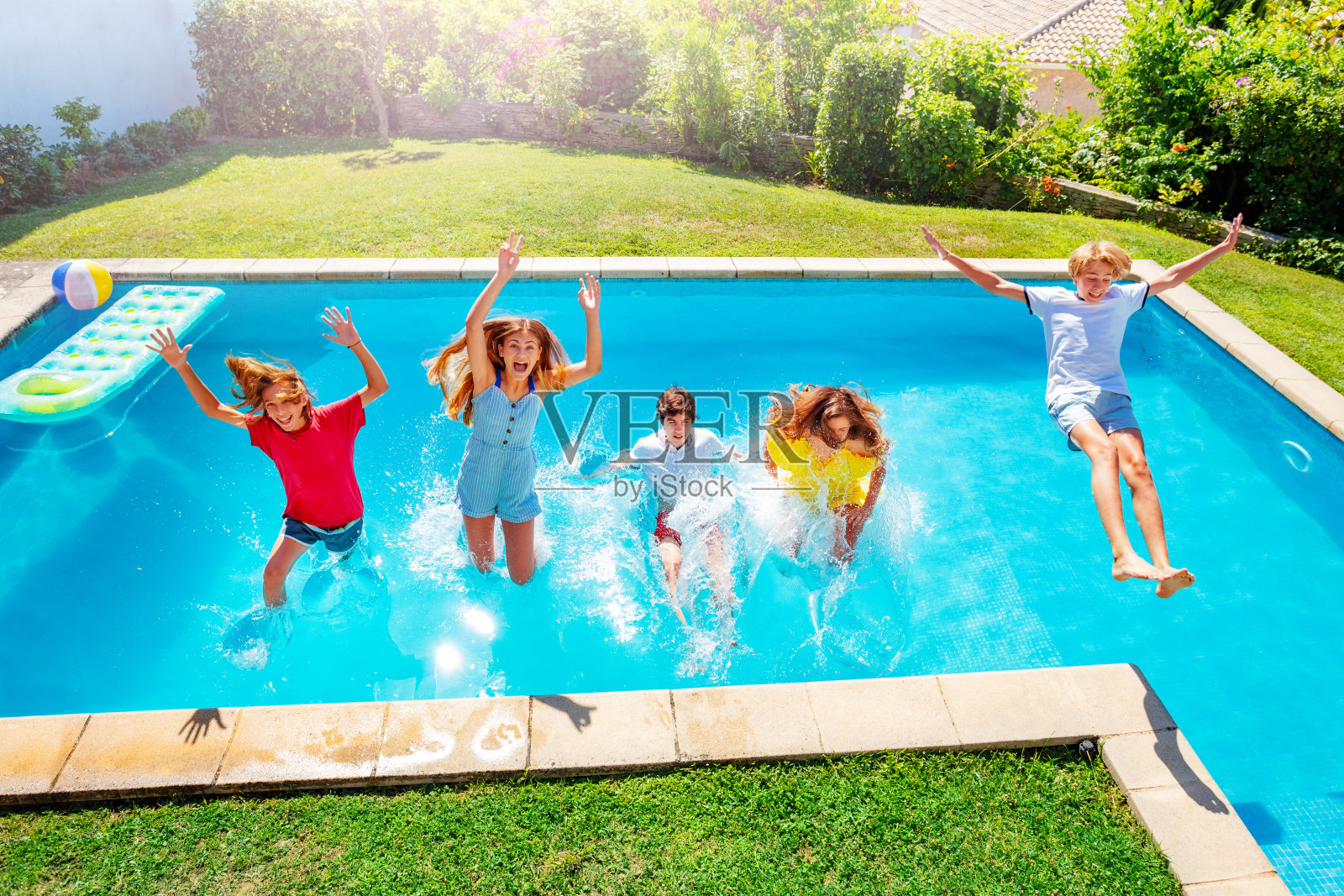 孩子们在半空中笑着掉进泳池里的水里照片摄影图片