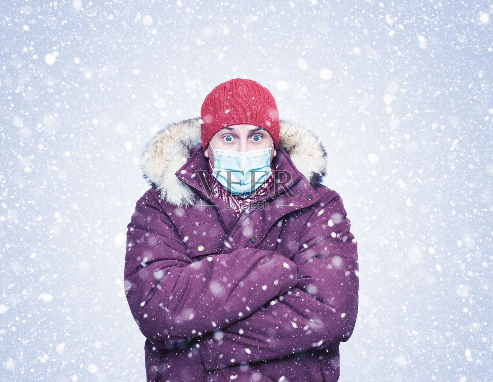 冻人穿着红色的冬衣在脸上戴着防毒面具，以抵御冠状病毒，雪地里到处都是照片摄影图片