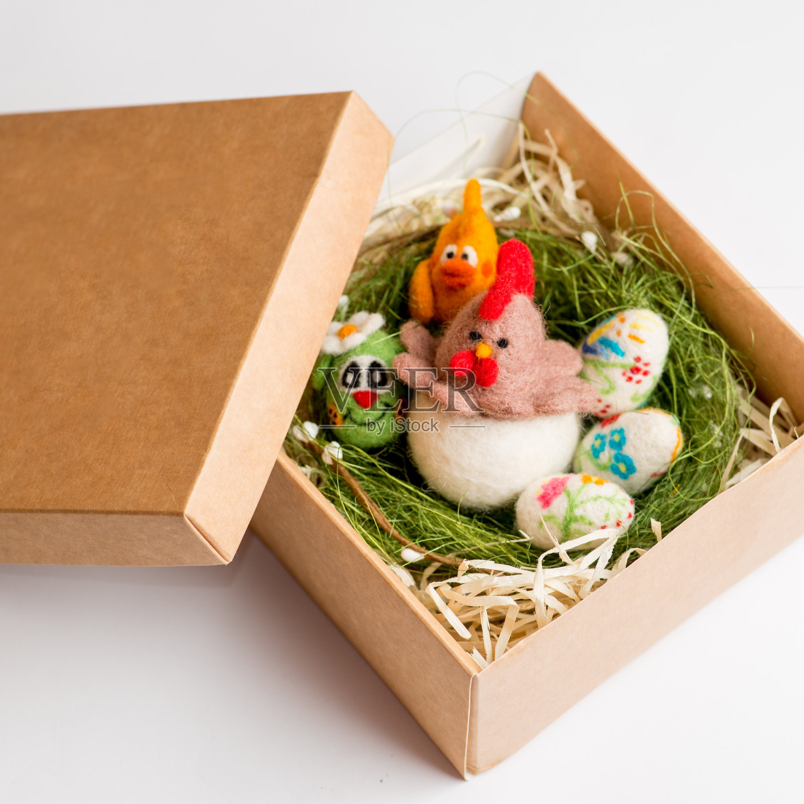 复活节的鸡和鸡蛋用羊毛制成，放在礼品盒里，背景是白色的。复活节的礼物包装照片摄影图片