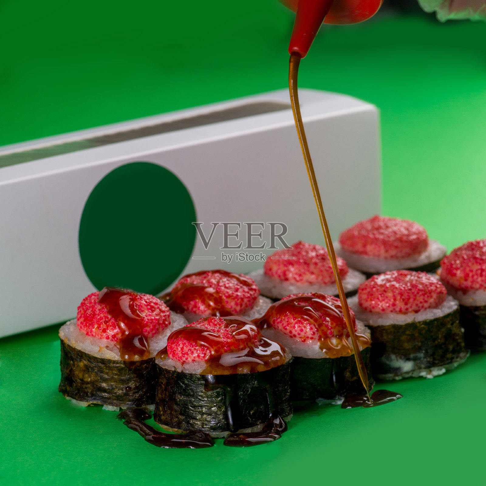寿司与海鲜海苔在绿色的背景。特写镜头。洒上红烧酱的寿司照片摄影图片