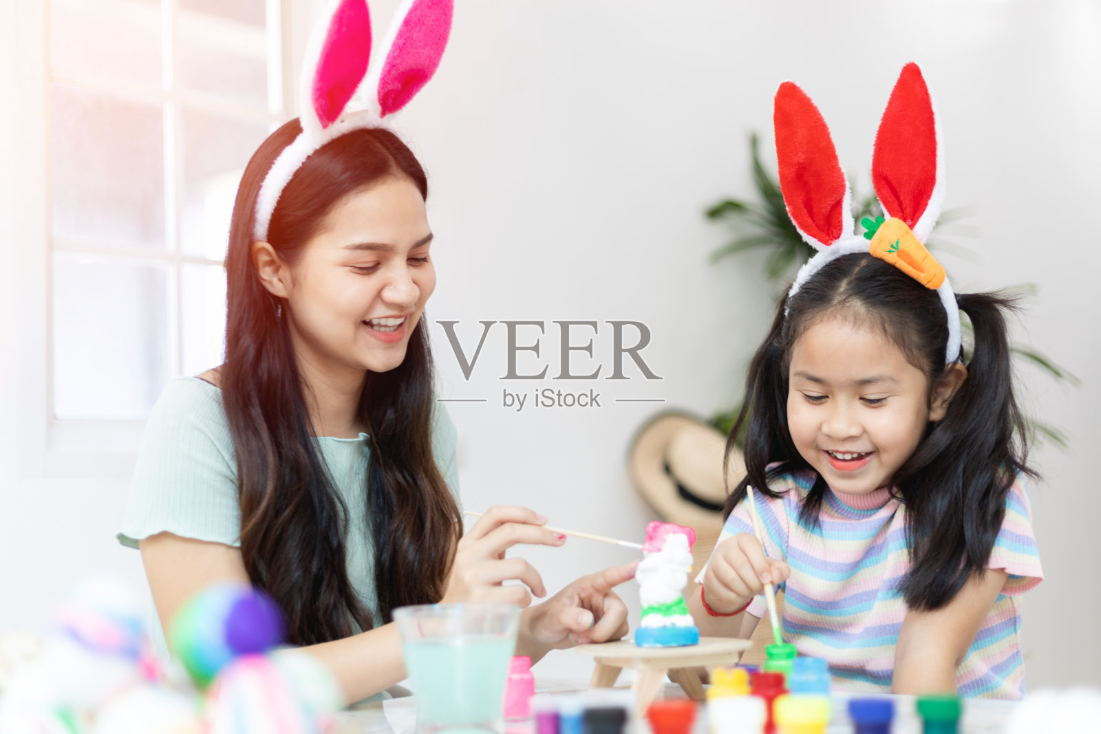 亚洲幼儿园的小女孩和妈妈在家里的客厅用丙烯水彩画石膏娃娃。家庭教育和远程教育。照片摄影图片