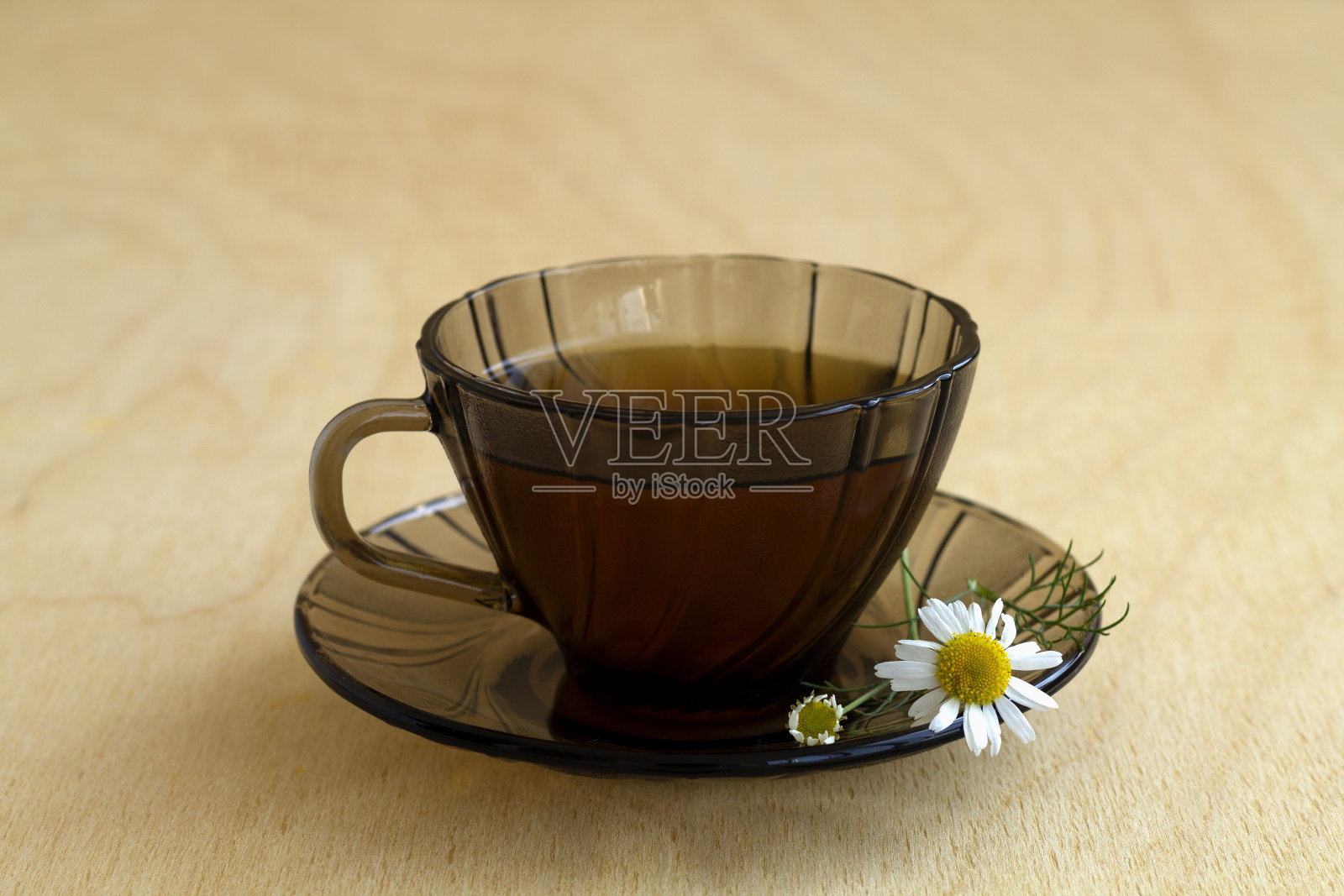 深色玻璃杯一杯草药茶和甘菊茶，放在一张有复印空间的浅色木桌上。一杯以鲜花为底色的茶照片摄影图片