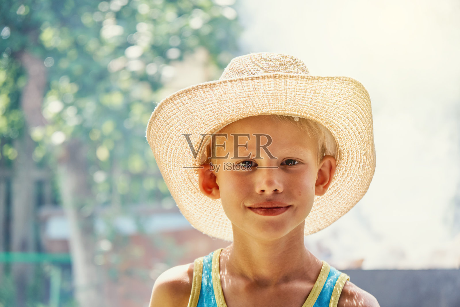 快乐的小男孩戴着大草帽在阳光明媚的夏日公园里照片摄影图片