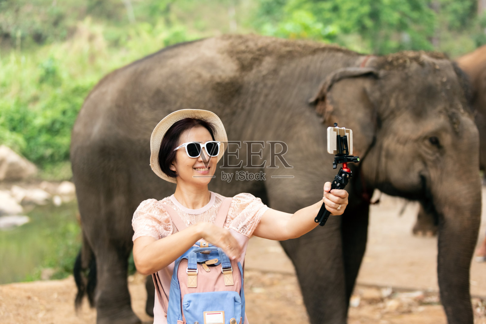 亚洲中年妇女旅游放松和拍照与大象在清迈，泰国。照片摄影图片