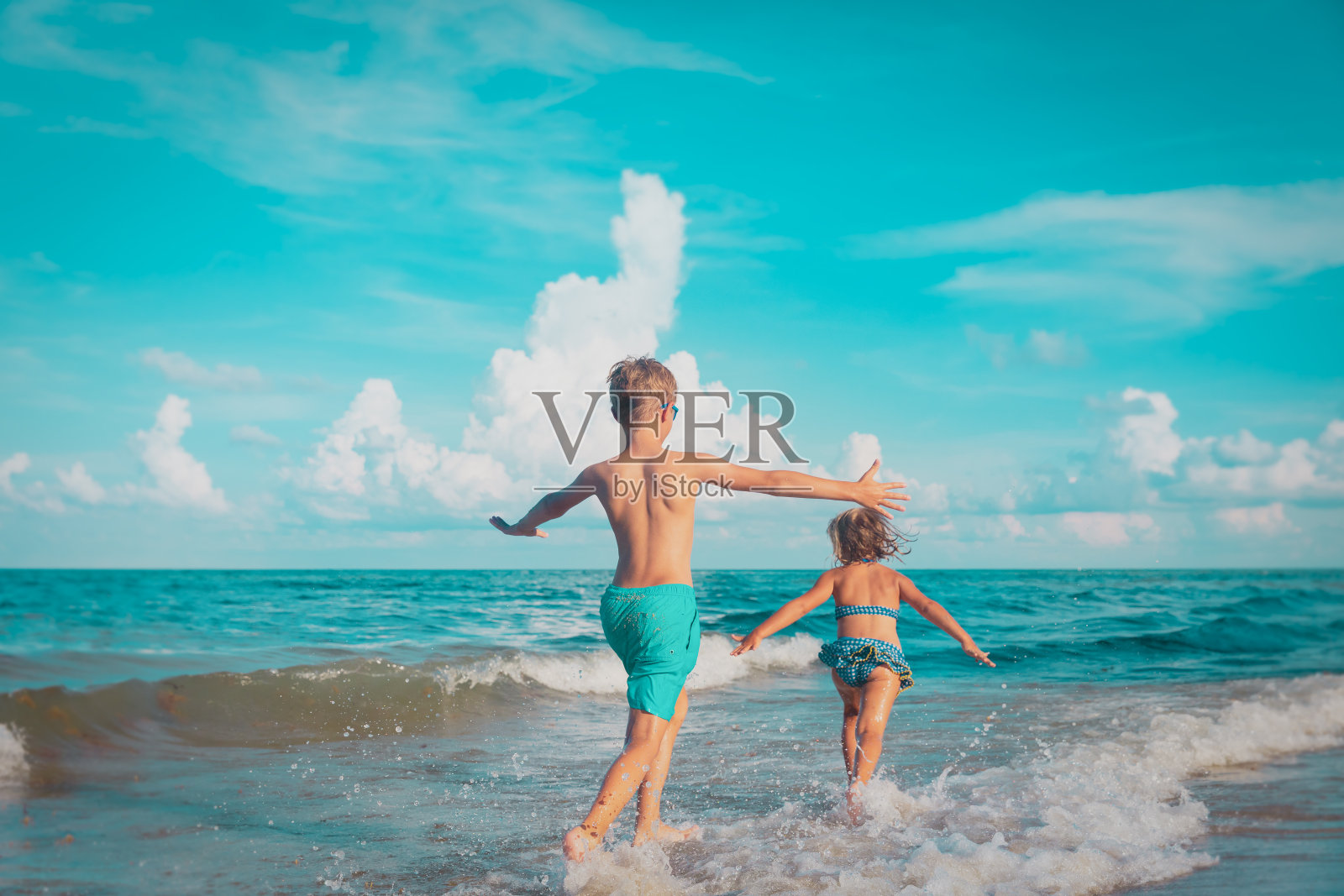 小女孩和小男孩在海滩上跑着玩水照片摄影图片