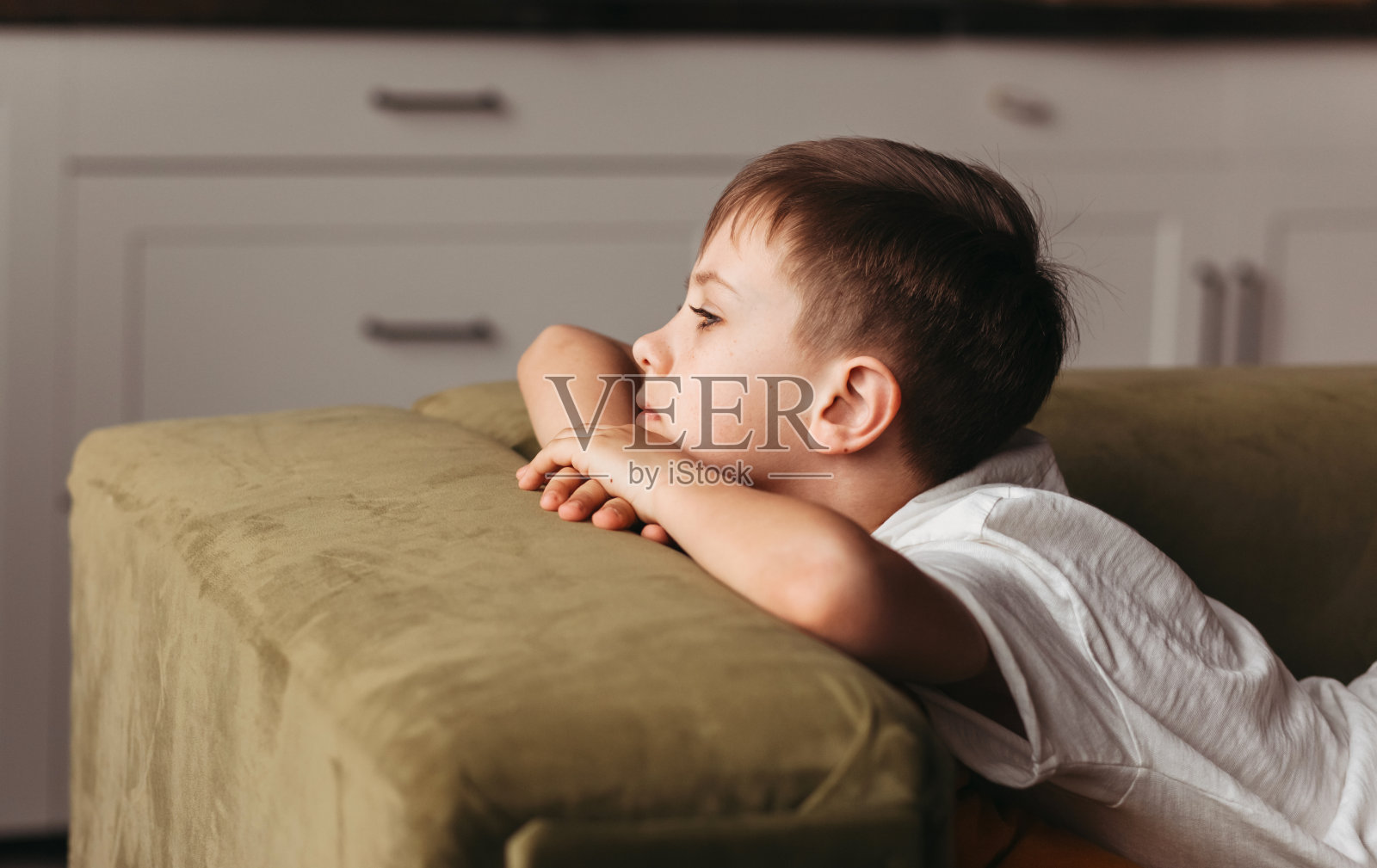 一个学龄男孩躺在家里的沙发上感到无聊，社交距离，隔离，孤立。锁定的概念。心理健康照片摄影图片