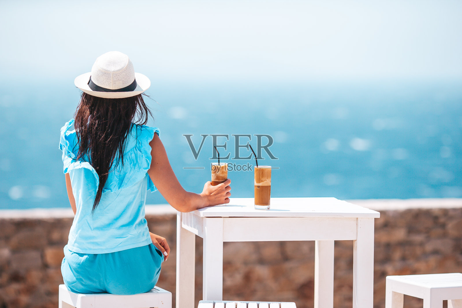 年轻女子喝着冷咖啡欣赏海景照片摄影图片