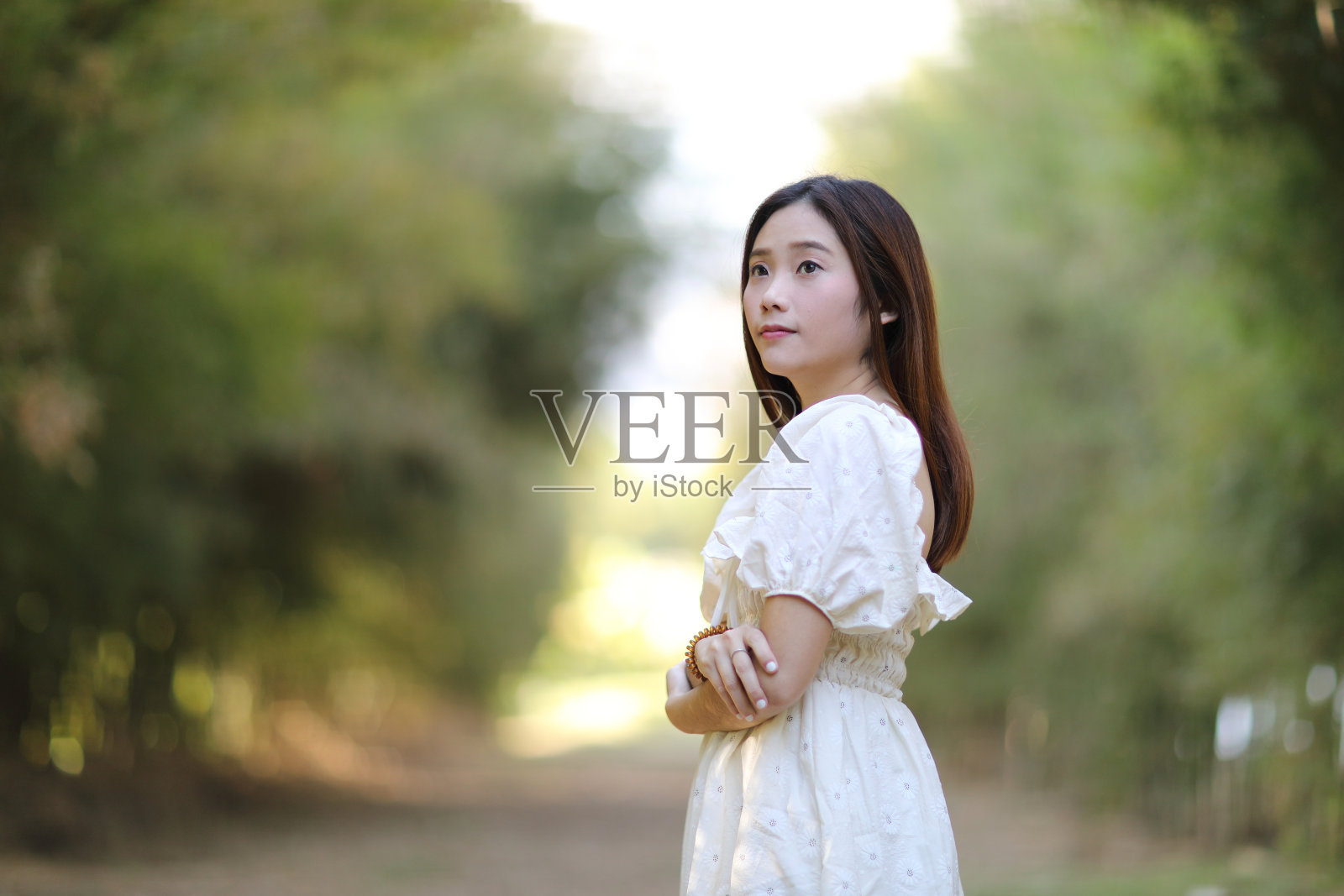 在花园背景上穿着白色衣服的美丽年轻女子照片摄影图片