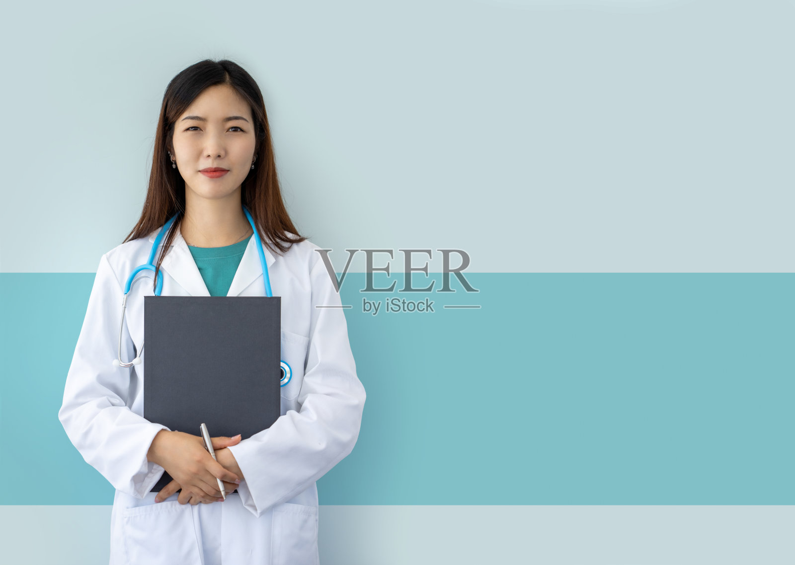 微笑的亚洲女医生与实验室大衣，听诊器和文件夹在浅蓝色的背景照片摄影图片