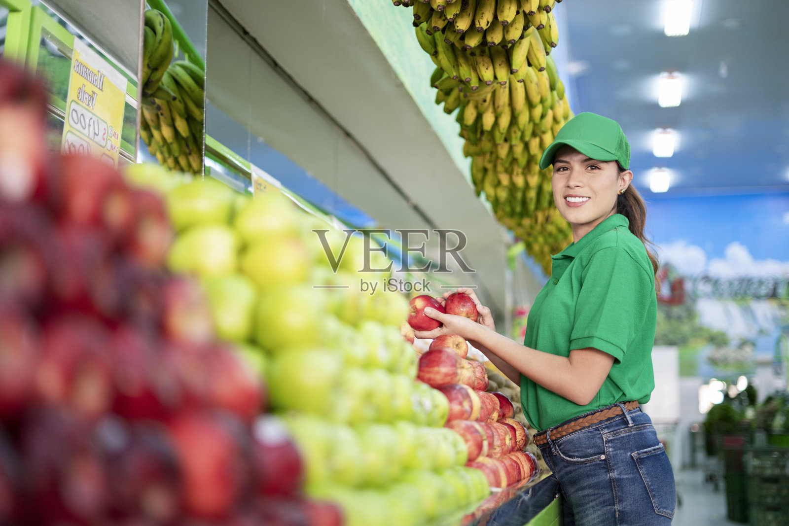 一位拉丁裔女子在杂货店里看着镜头，一边整理着她的水果和蔬菜照片摄影图片
