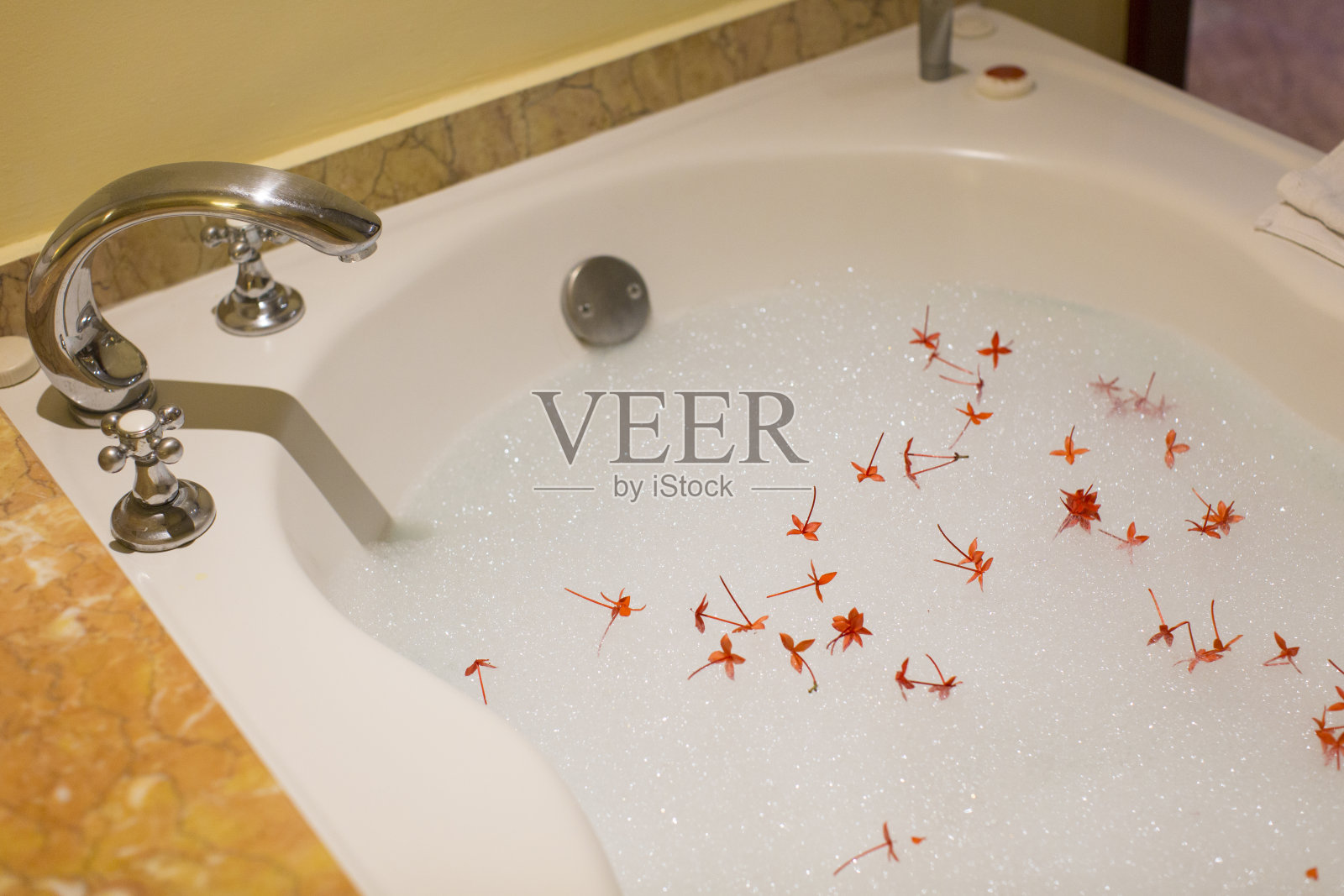 白色浴缸上有泡沫和花瓣的洗澡水，穿着蜜月套装照片摄影图片