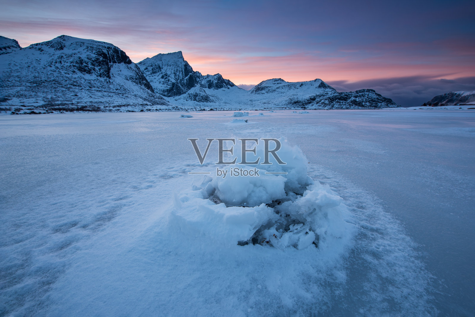 挪威罗浮敦群岛，美丽的景观开裂的冰，冰冻的海岸与山脉背景在冬季日落照片摄影图片