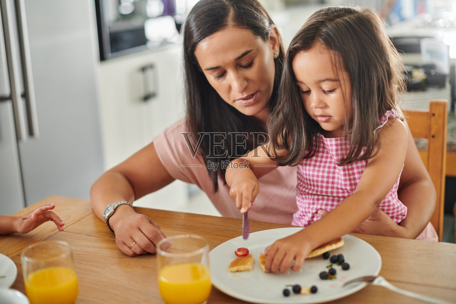 一个可爱的小女孩和她的妈妈在家里吃煎饼当早餐照片摄影图片