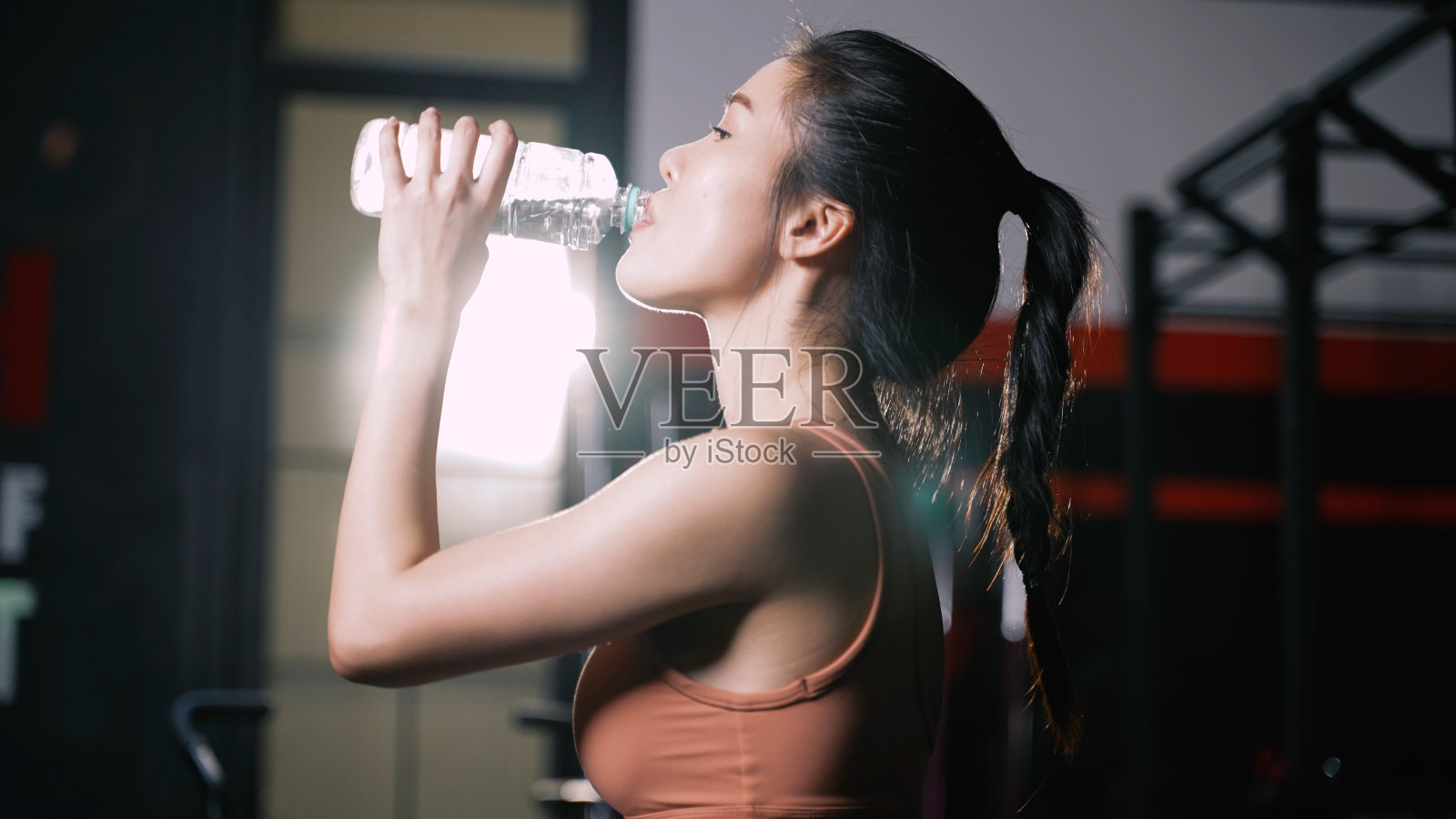 运动员亚洲妇女饮用纯净水后锻炼或训练建立肌肉和燃烧脂肪心脏，刷新身体健康的生活方式在健身馆。照片摄影图片