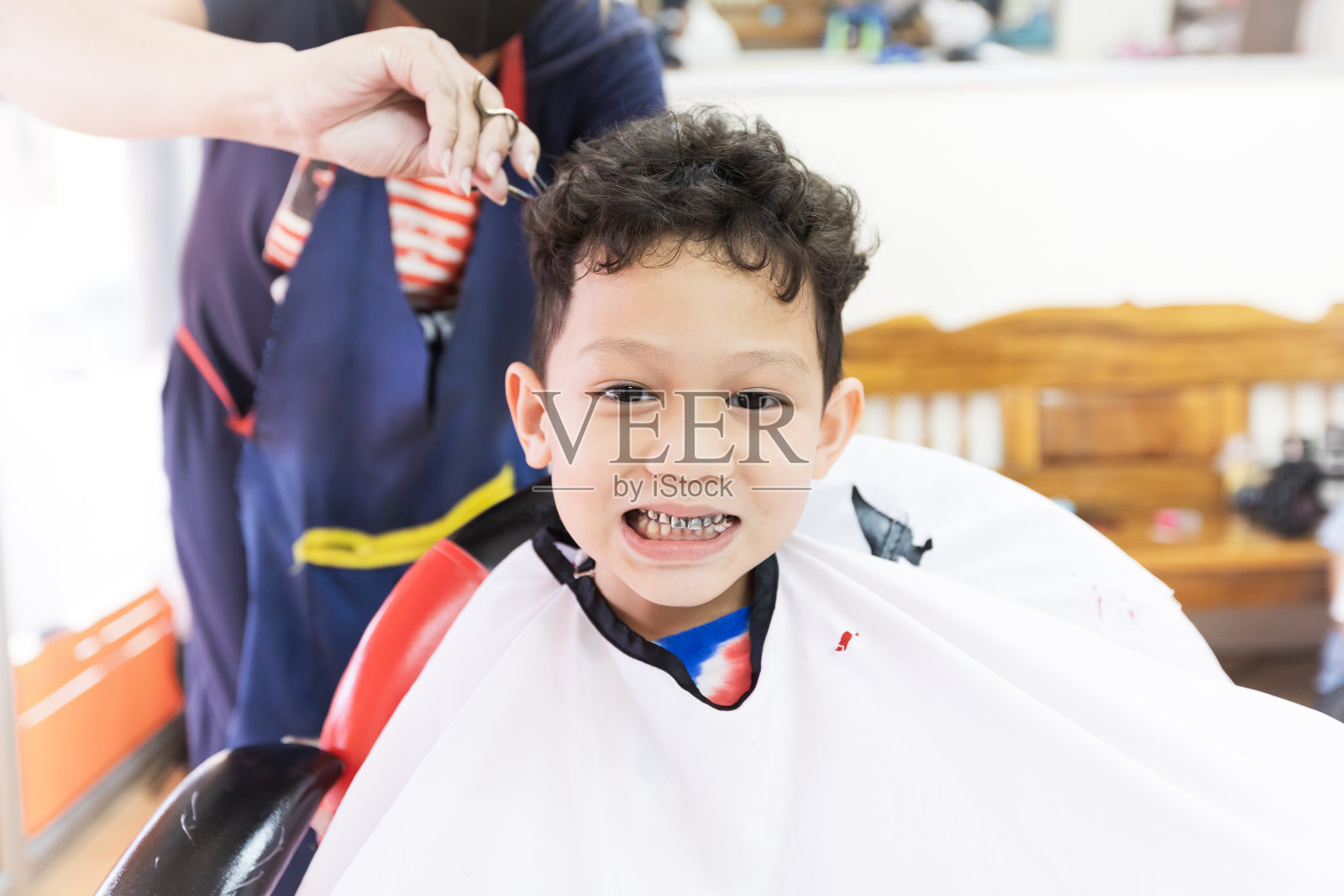 可爱的亚洲小男孩正在美发店理发。照片摄影图片
