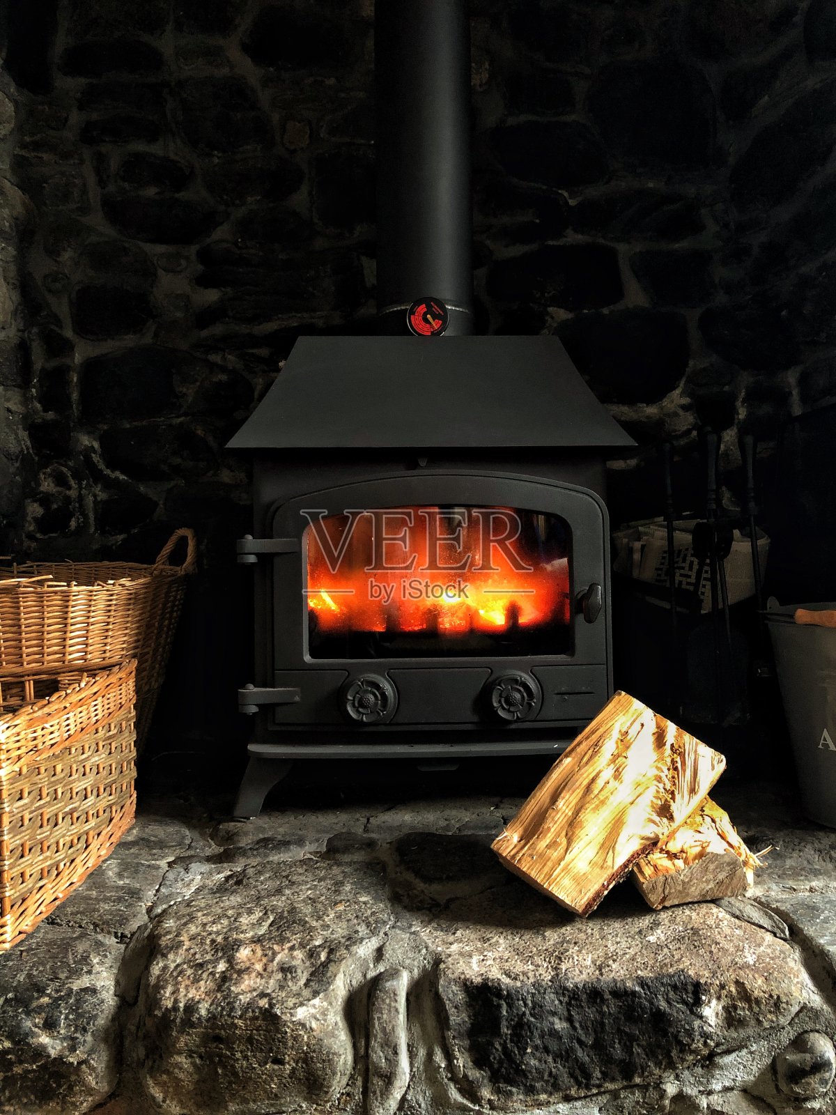在一间舒适的石头小屋里有一个燃烧木材的火炉，壁炉里燃烧着熊熊的火焰照片摄影图片