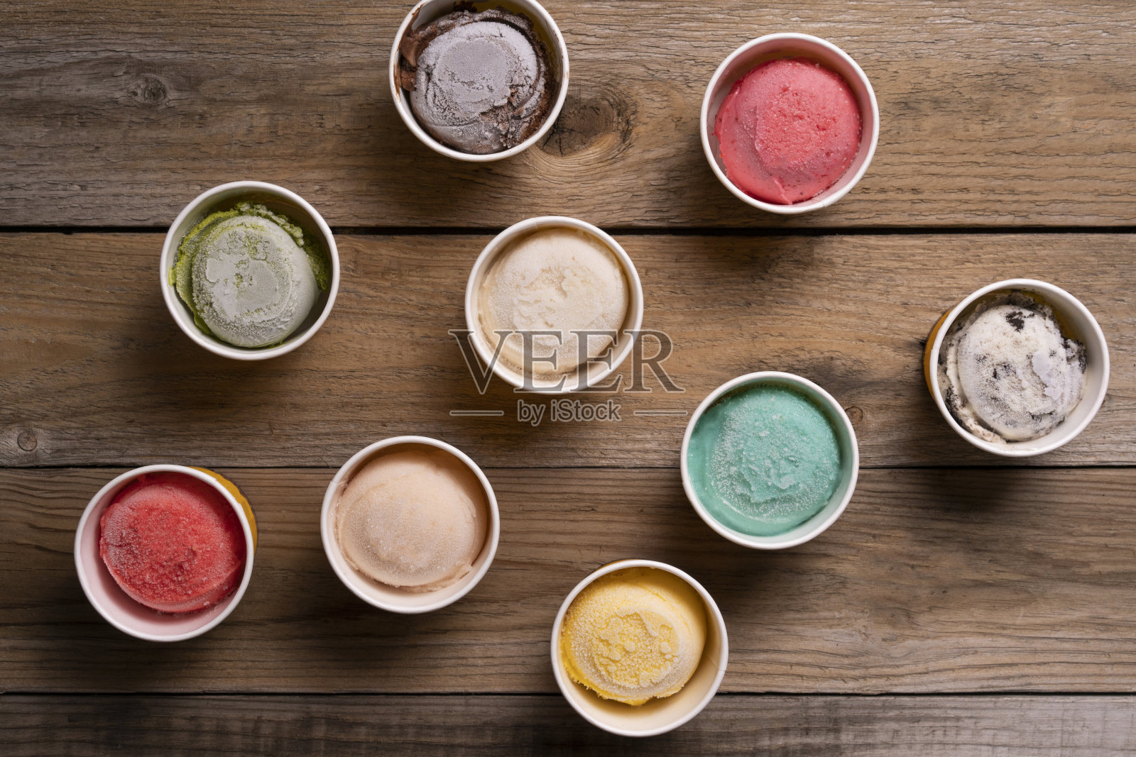 顶视图或平铺冰淇淋口味的杯子和顶部在木桌上，甜和甜点食品的概念照片摄影图片