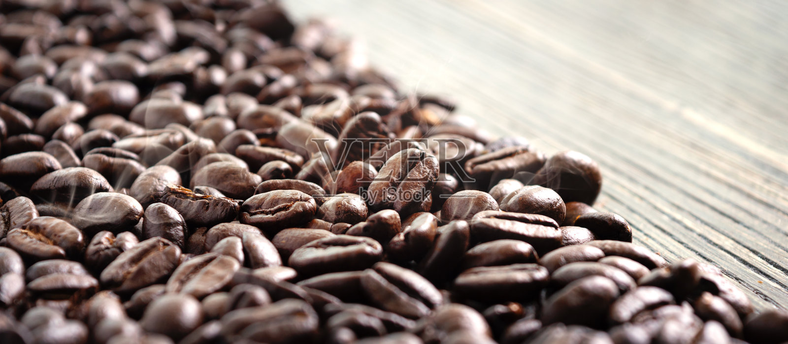 新鲜烘焙的咖啡豆，烟熏。有选择性的重点。新鲜芳香咖啡的概念。照片摄影图片