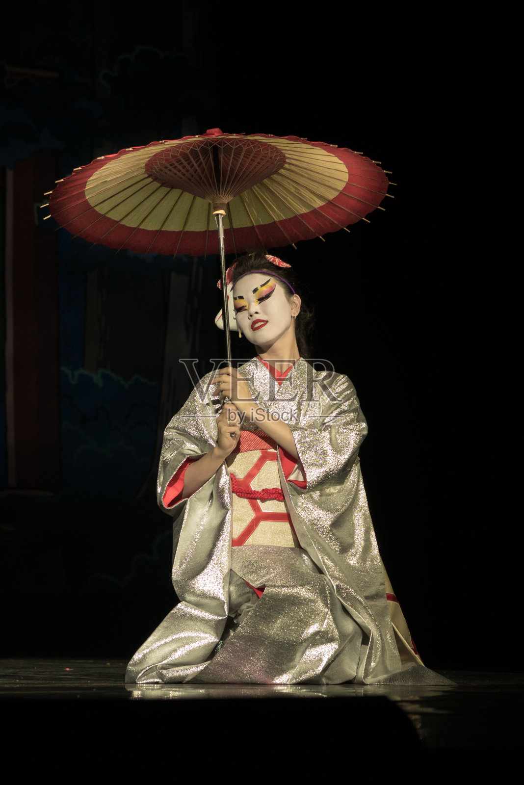 穿着传统和服、撑着伞坐在膝盖上的日本妇女照片摄影图片
