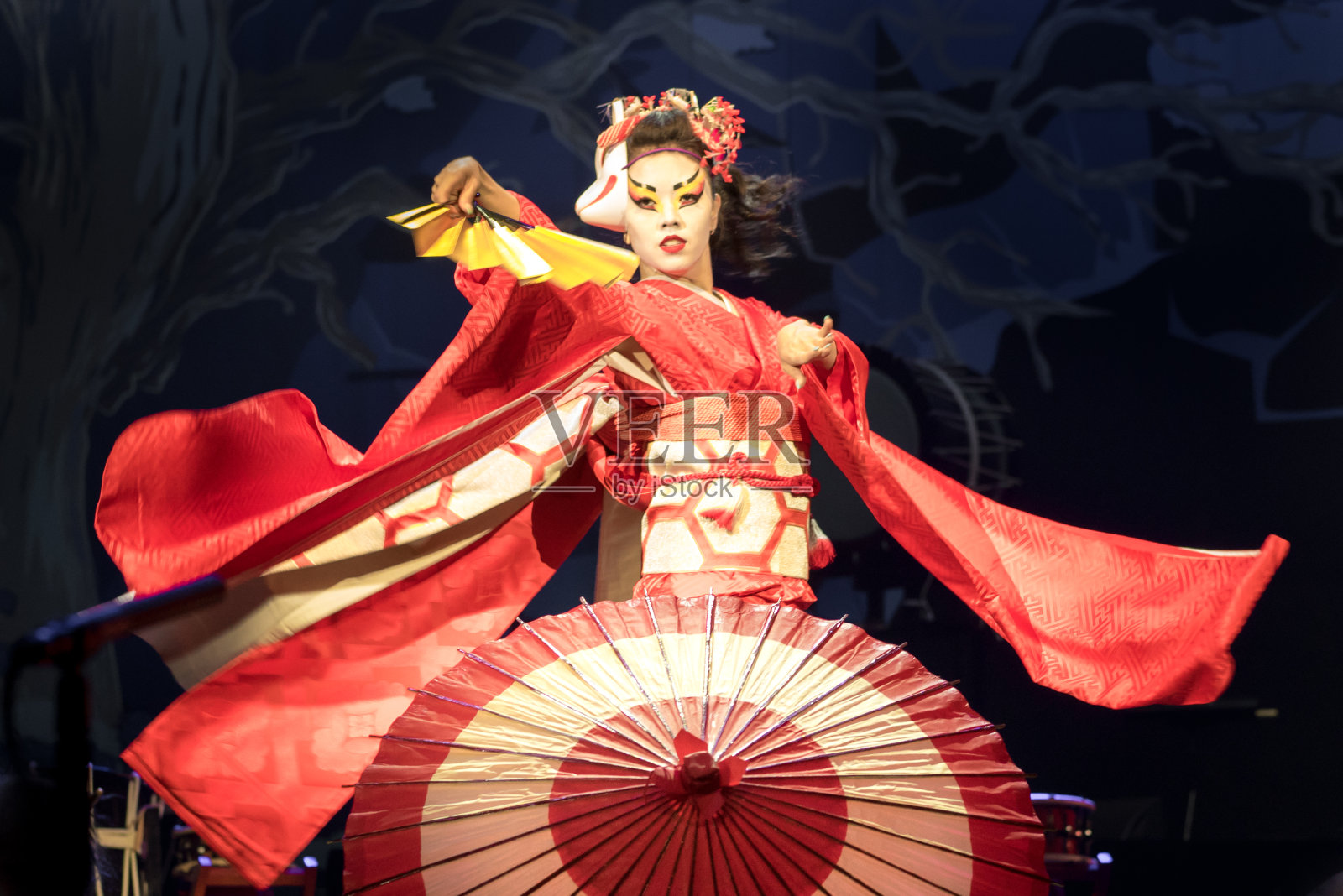 女子舞动着扇子和伞，衣袖飘逸。传统的日本表演红狐舞。野狐是日本传说中的一个人物。照片摄影图片