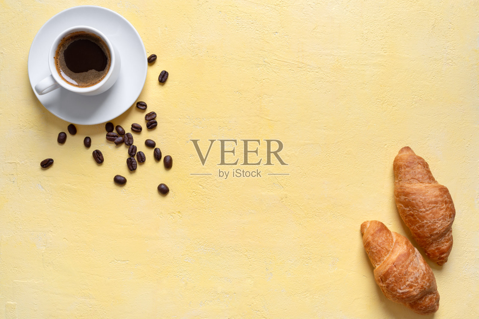 一杯新鲜的咖啡和羊角面包，背景是黄色的，有复印空间。食物背景以咖啡为主题，早餐菜单，早上好心情。照片摄影图片