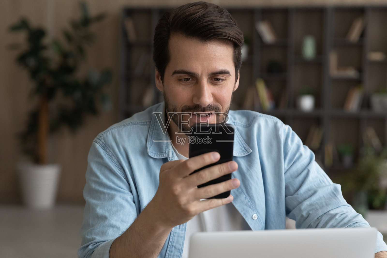 微笑的年轻商人在办公室使用智能手机。照片摄影图片