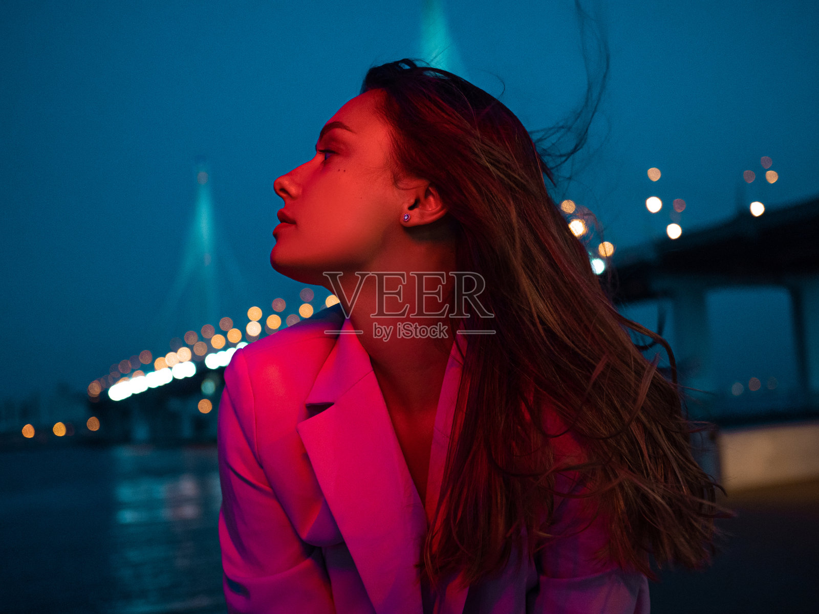 一个年轻时尚的黑发女郎在夜城的霓虹灯下，照片摄影图片