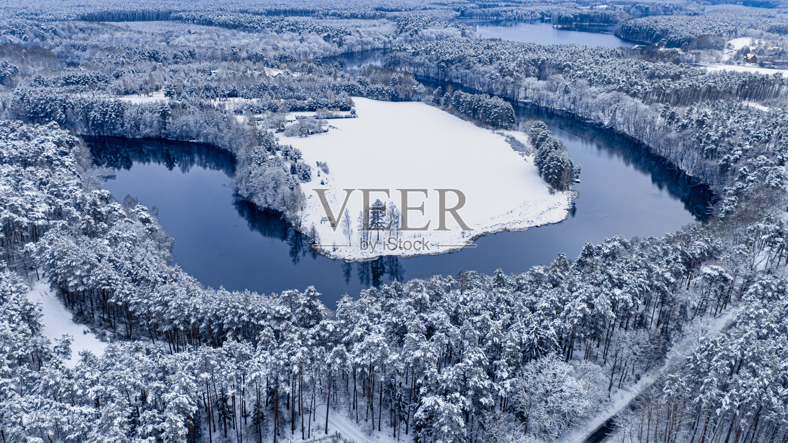 在冬天，在弯弯曲曲的河流和白雪皑皑的森林上空飞翔。照片摄影图片