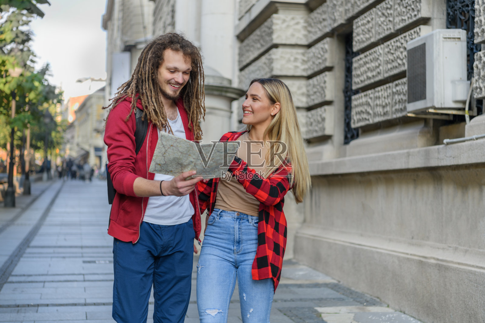 一个年轻人和他的女朋友带着旅游地图在市区散步。照片摄影图片
