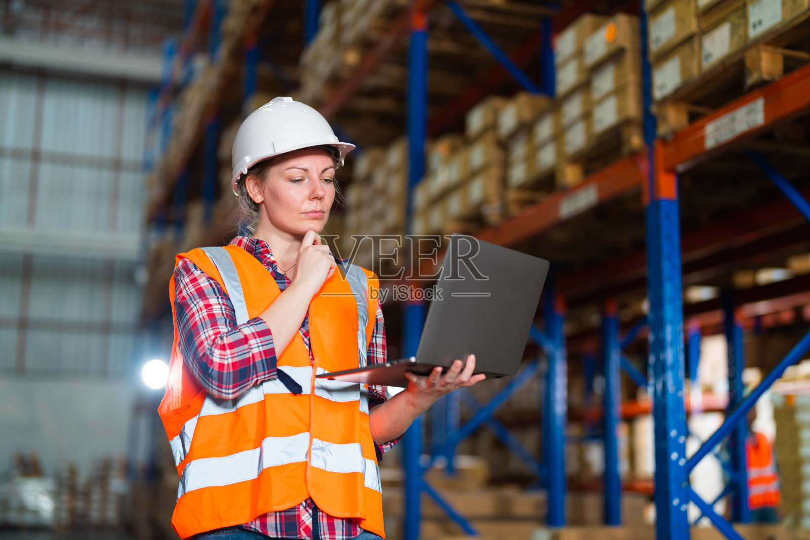 仓库工人在大型仓库配送中心使用笔记本电脑检查包裹的工作过程。照片摄影图片