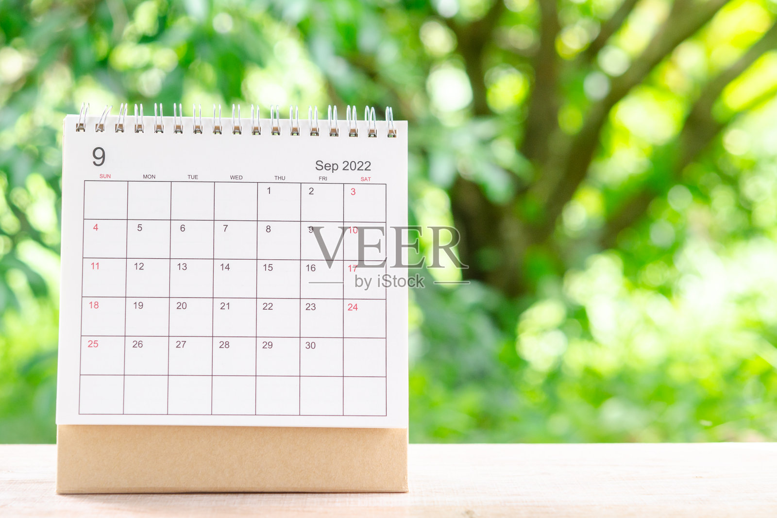 2022年9月，以绿色自然为背景的木桌日历，供主办方规划和提醒。照片摄影图片