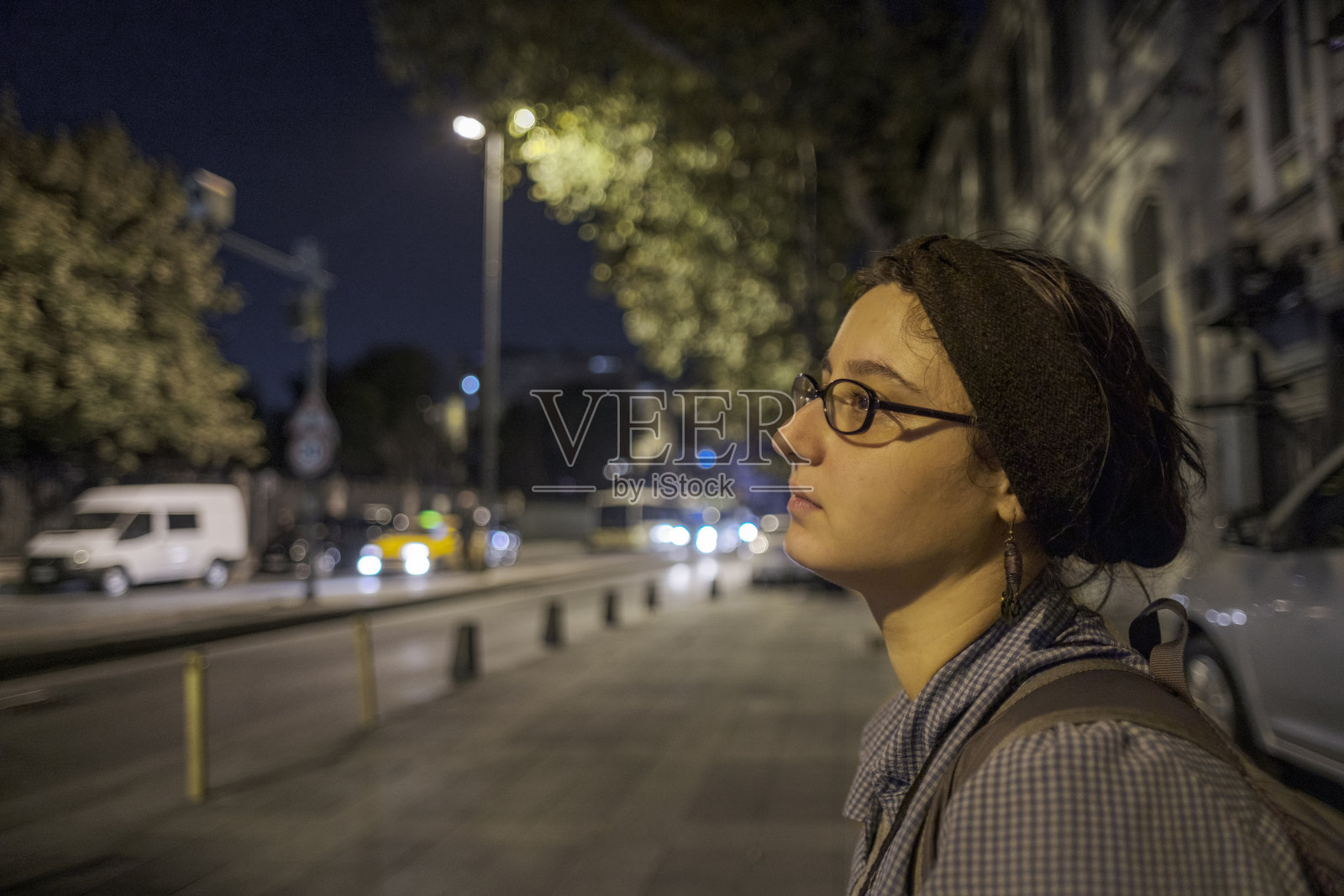 一个年轻女子在晚上独自在外面找公共汽车或出租车照片摄影图片