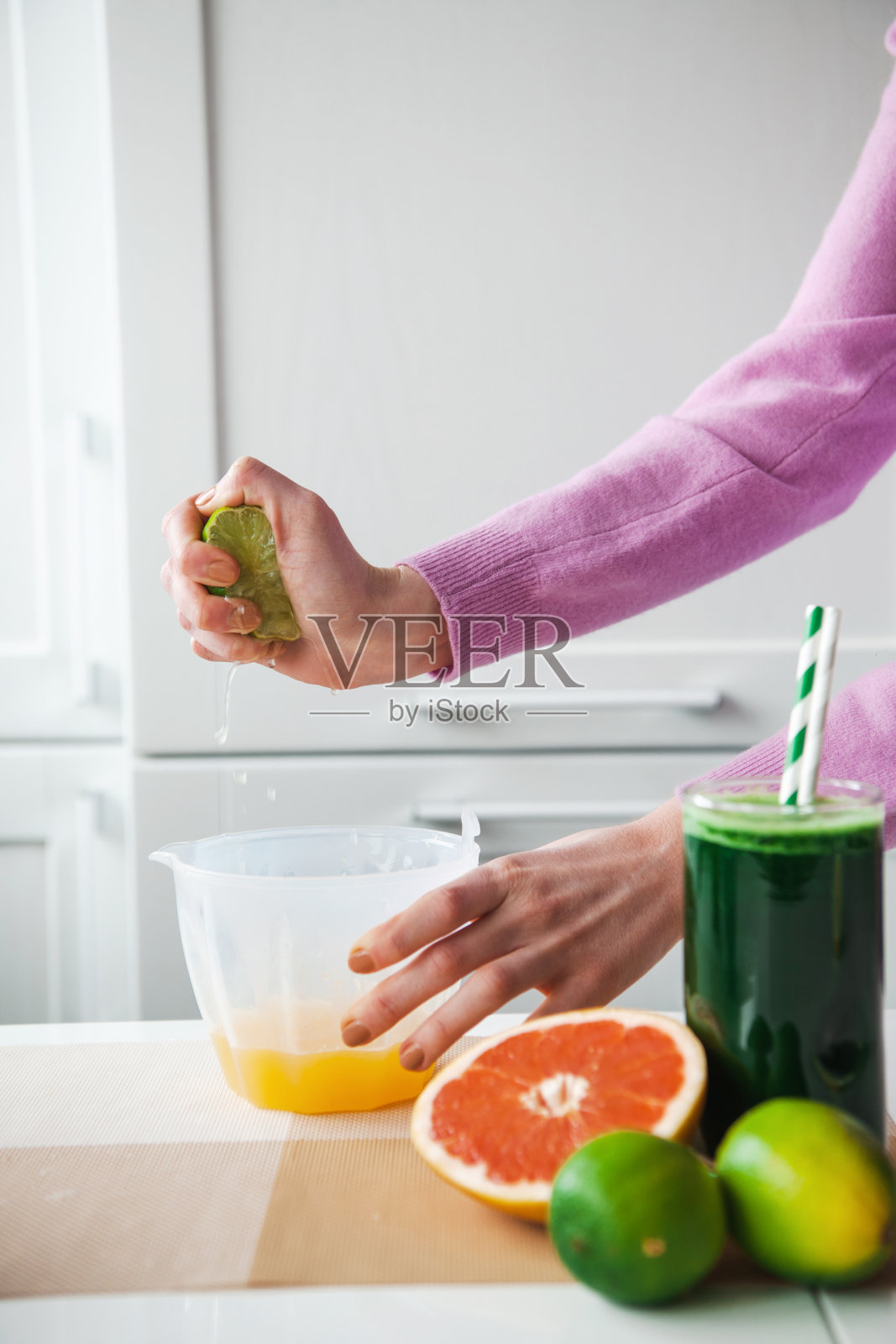 一名妇女在厨房里挤柠檬汁的特写照片。在厨房里挤点柠檬汁。果汁。节食与健康饮食观念。照片摄影图片